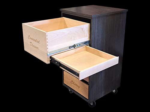A cabinet on wheels with a drawer pulled out with a concealed drawer box underneath it